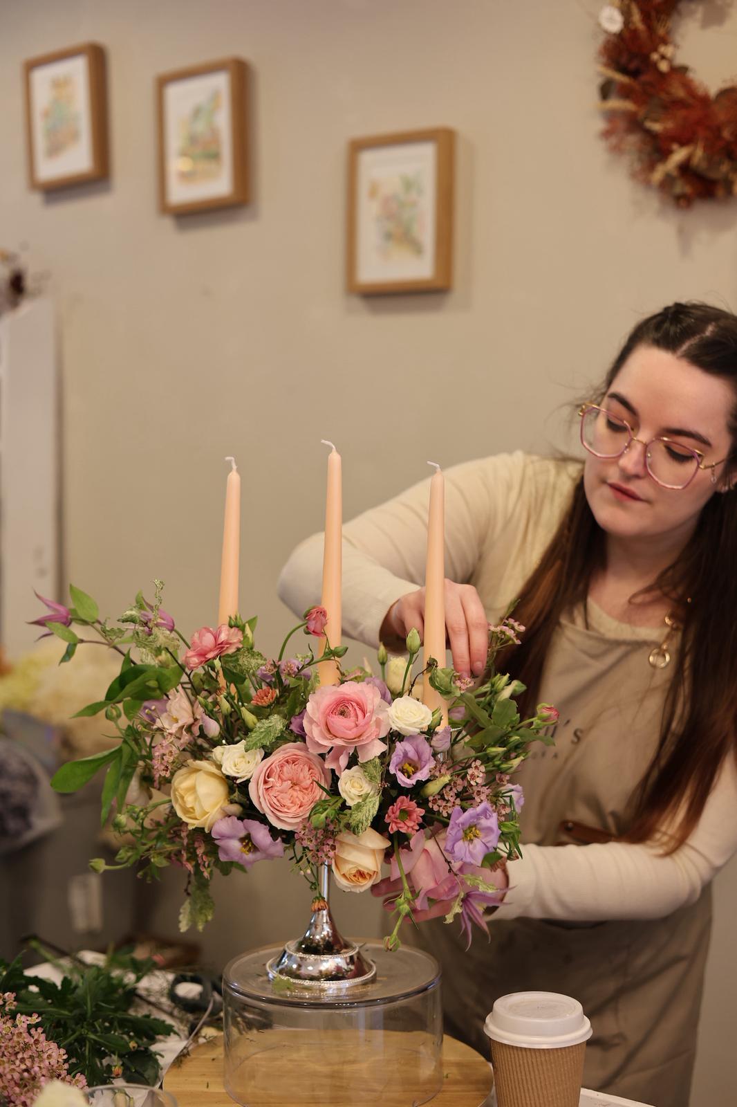 Jordan, owner of Blooming Edens, arranging flowers on a table.