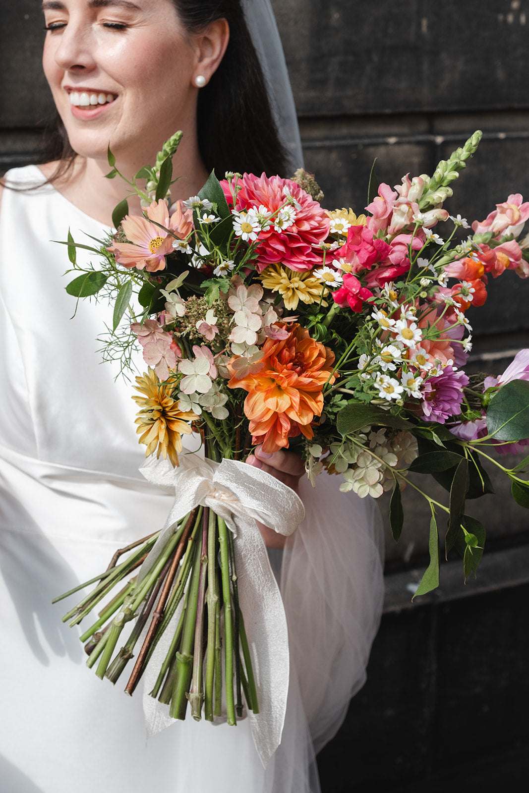 Bride holding a colorful bouquet of flowers against a dark background